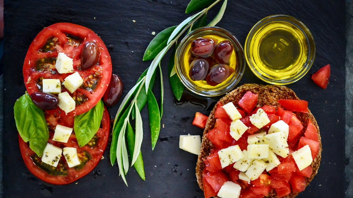 A vibrant Greek salad featuring tomatoes, feta, and olives on a slate board, perfect for healthy eating.